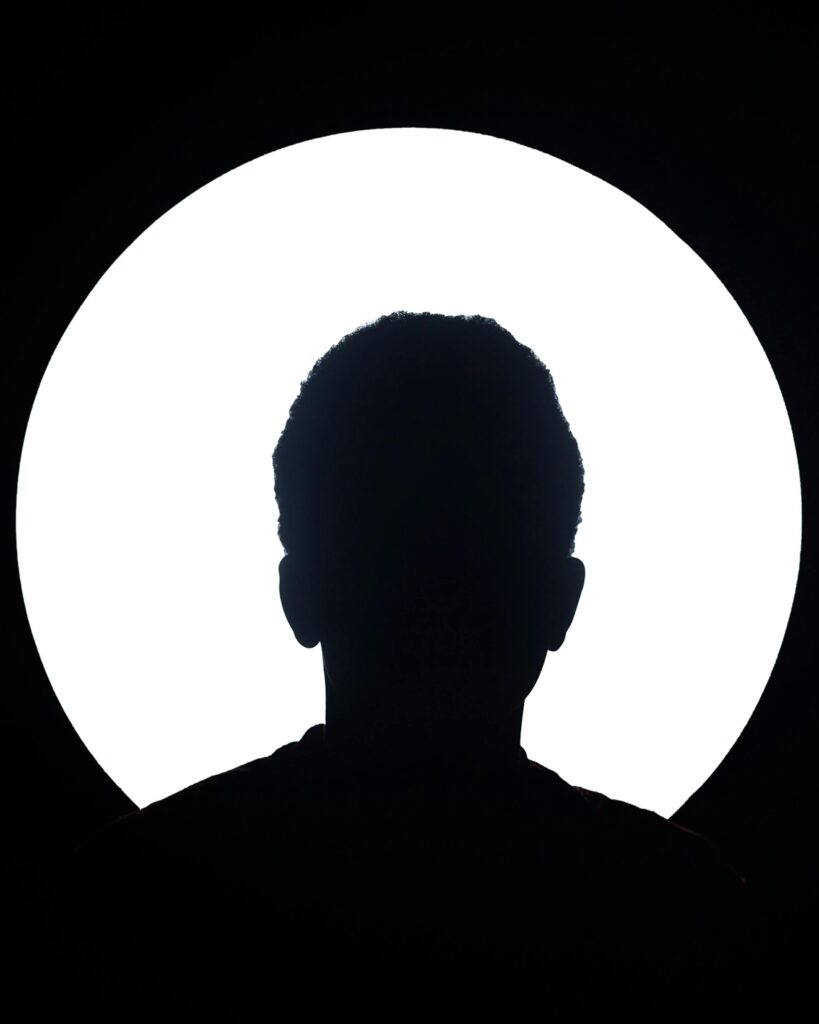 Artistic silhouette of an unknown person against a bright circular light background.
